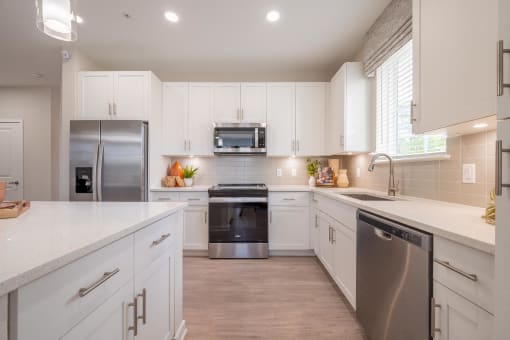 a large kitchen with white cabinets and stainless steel appliances
