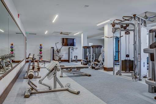 a gym with weights and other exercise equipment in a room with a tv