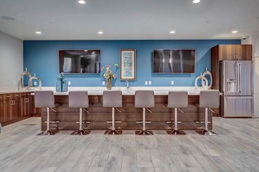 a kitchen with a bar and chairs in front of a blue wall