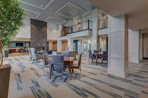 a large lobby with tables and chairs and a fireplace