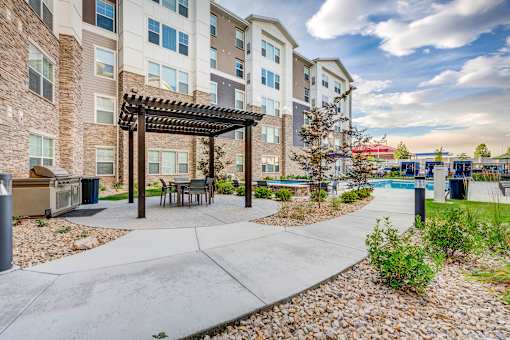 an outdoor patio with a picnic area and a pool at an apartment building