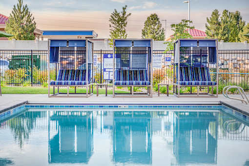 a swimming pool with blue lounge chairs next to it