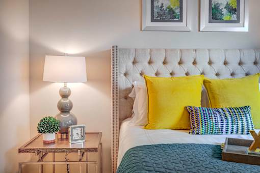 a bedroom with a bed and yellow pillows and a nightstand with a lamp