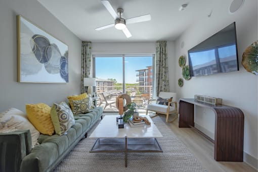 a living room with a couch and a ceiling fan and a window