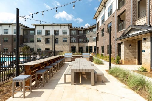 an outdoor patio with tables and benches at a building with a pool