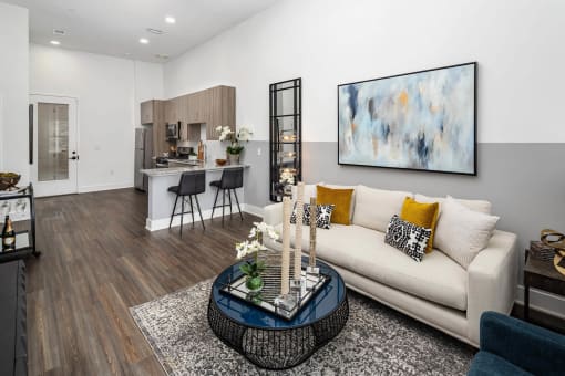 A modern living room with a white couch and a large abstract painting on the wall.