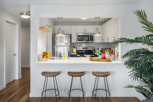 a kitchen with a bar and stools in a 555 waverly residences apartment