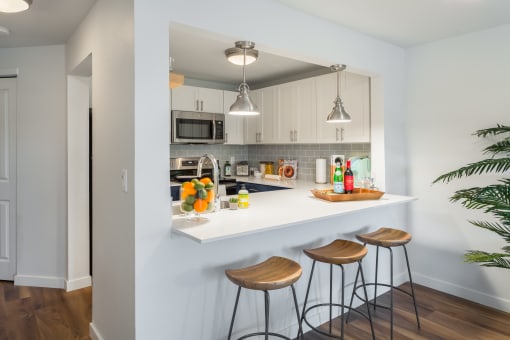 a kitchen with a white counter top and three stools