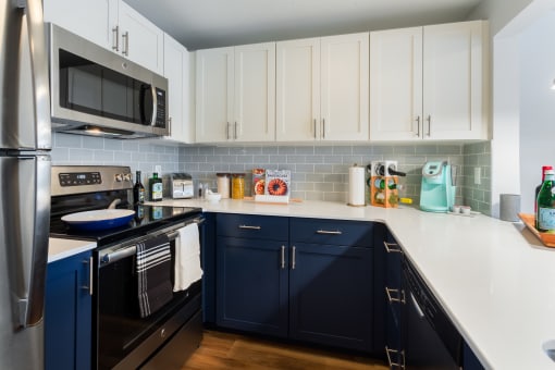 a kitchen with navy cabinets and white countertops and a stainless steel refrigerator