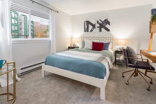 a bedroom with a bed and a desk and a window