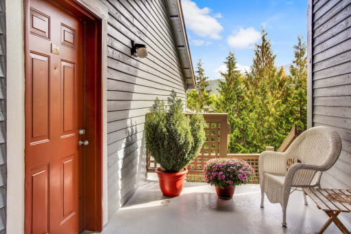 front porch with chairs and plants and a door