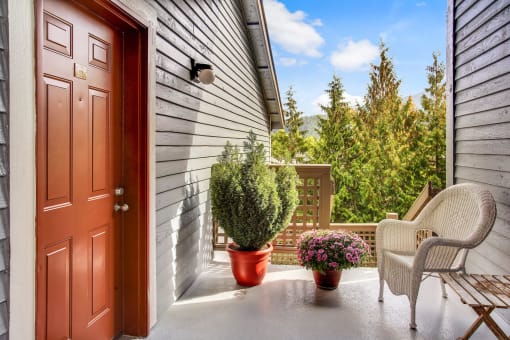 front porch with chairs and plants and a door
