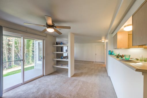 a kitchen and living room with a ceiling fan and a window
