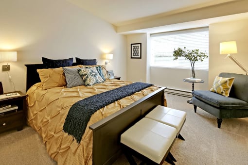 a bedroom with a bed and a chair and a window