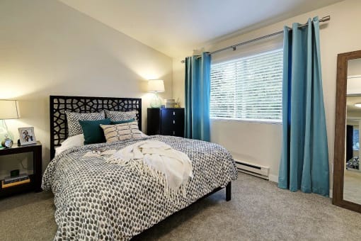 a bedroom with a bed and a window with blue curtains