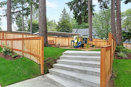 a wooden fence with stairs and a playground in a yard