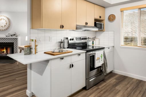 a kitchen with white cabinets and a stove and a fireplace