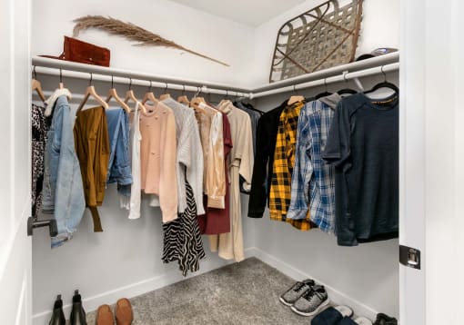 a closet with a rack of clothes and shoes