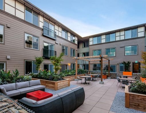 a patio with a couch and tables in a courtyard