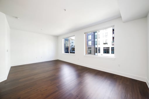 an empty living room with wood floors and two windows