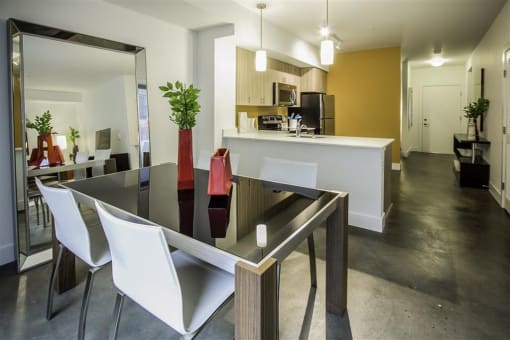 a dining room table with white chairs  and a kitchen