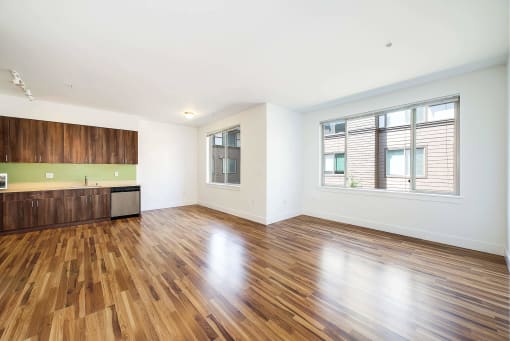an empty living room with wood flooring and a window