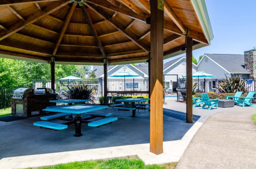 a picnic pavilion with benches and picnic tables in a park