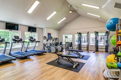 a gym with cardio equipment and weights on a wooden floor