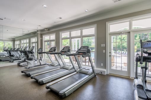 the gym is equipped with cardio equipment and windows