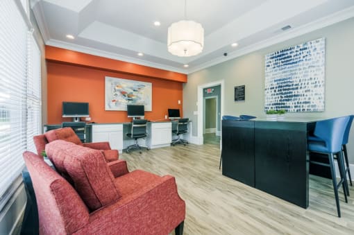a reception area with red chairs and a desk with computers