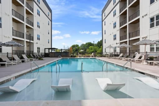 a swimming pool with chairs in front of a building