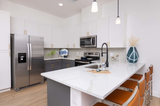 a kitchen with a large island with quartz countertops and stainless steel appliances at Element 12 Apartments, Henderson NV