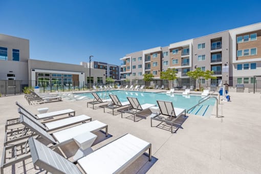 a pool with lounge chairs and umbrellas in front of an apartment building at Element 12 Apartments, Henderson NV