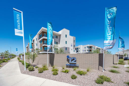 a building with flags and a sidewalk in front of it at Element 12 Apartments, Henderson NV