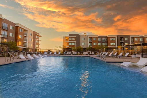 Evening pool lounge area with chairs and a sunset background at Element 12 Apartments, Henderson NV