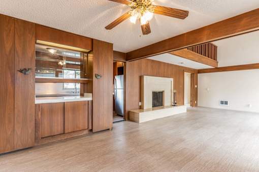 an empty living room with a fireplace and a ceiling fan at Hillsdale Garden Apartments, San Mateo, California