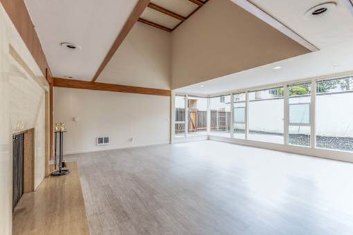 an empty living room with a fireplace and a large window at Hillsdale Garden Apartments, San Mateo