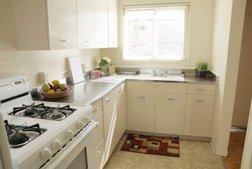 a kitchen with white cabinets and a stove and a window at Hillsdale Garden Apartments,California 94403