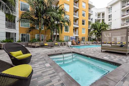 A pool surrounded by chairs and palm trees.