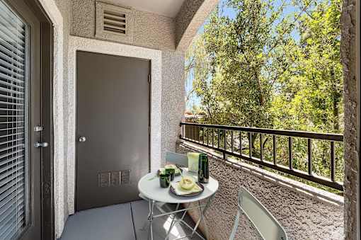 A balcony with a table and chairs and a bottle of wine.