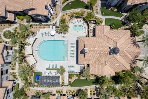 An aerial view of a resort with a swimming pool and palm trees.