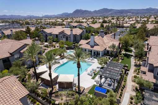 A large swimming pool surrounded by palm trees and apartment buildings.