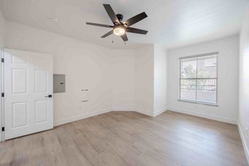 A room with a ceiling fan and a window with blinds.