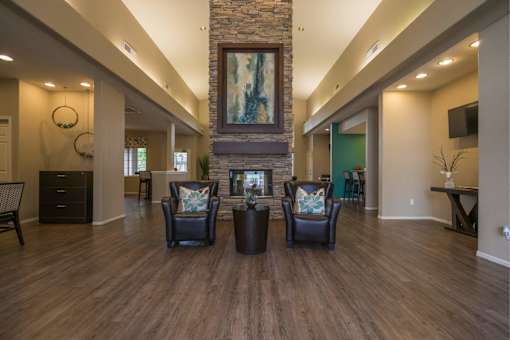 A living room with a stone fireplace and two chairs.