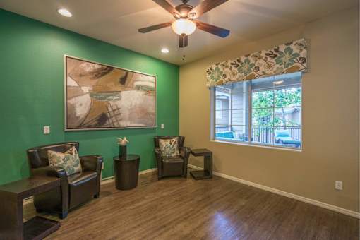 A living room with a green wall and a painting hanging on it.