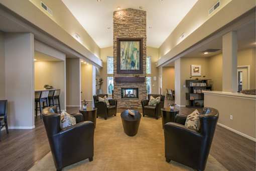A living room with a stone fireplace and leather chairs.