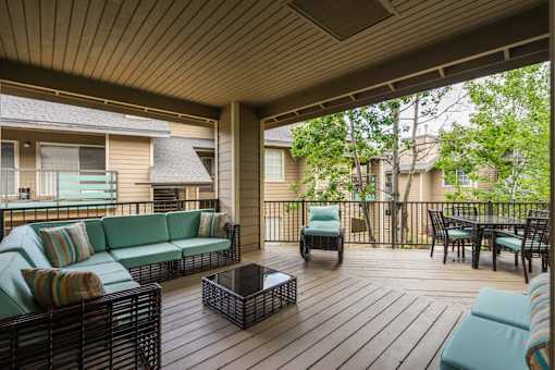 A wooden deck with a sofa and chairs.