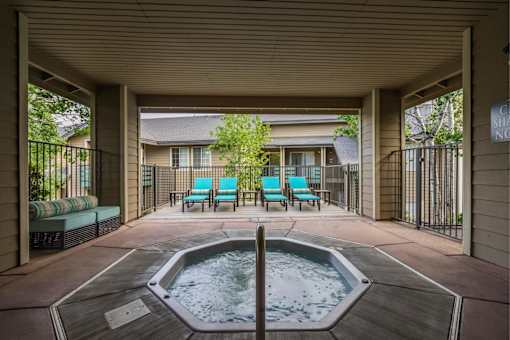 A hot tub is in the middle of a patio with chairs around it.
