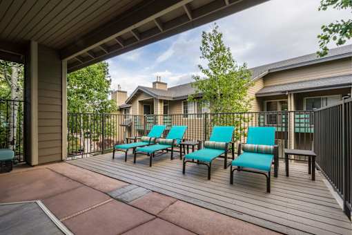 A patio with blue chairs and a table.