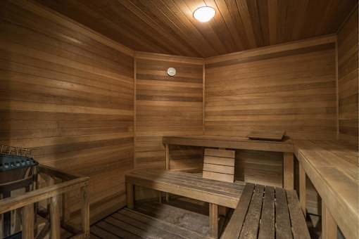A wooden sauna with a bench and a bucket.